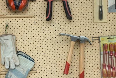 black and silver claw hammer beside red and black hand tool